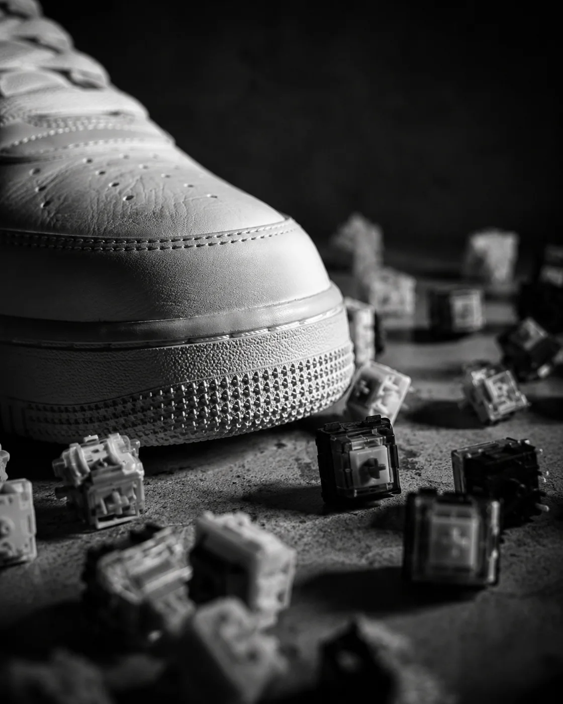 Monochrome close-up of a sneaker surrounded by keyboard switches